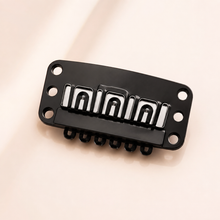 Single black Signature Grip extension clip with six sewing holes and silver spring insert